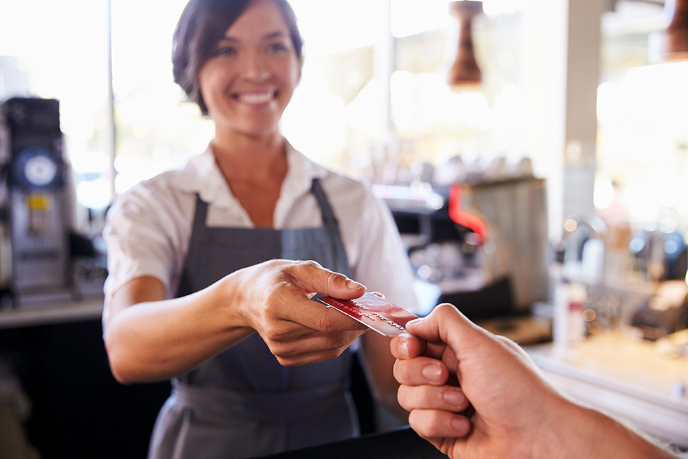 Cashier Accepts Card Payment From Customer In Delicatessen