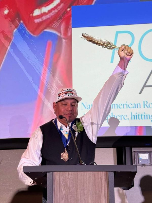 Anderon holds an eagle feather aloft at last month's ceremony. (photo/Greg Winkels)