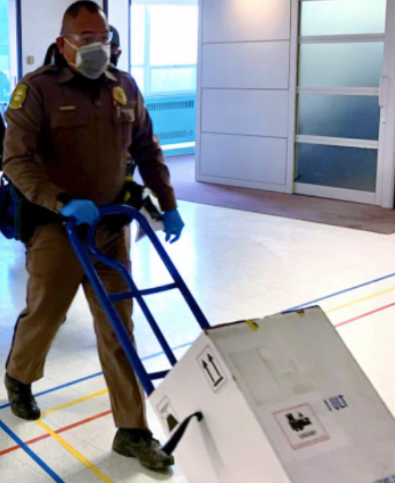 Navajo Nation Police Officer Jershon Begay transports the first delivery of COVID-19 vaccines to an ultra-cold freezer at the Indian Health Service's Gallup Indian Medical Center in Gallup, New Mexico, December 14, 2020.