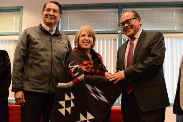 Navajo Nation President Jonathan Nez, Gov. Michele Lujan Grisham, and NTU President Dr. Elmer J. Guy take a photo as Governor Lujan Grisham is presented with a NTU Pendleton blanket.