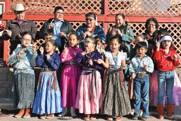 NAVAJO TIMES | RIMA KRISSTYá'át'ééh Késhmish! Delegates Wilson Stewart, Nathanial Brown and Amber Kanazbah Crotty join Tséhootsooí Diné Bi'Ólta' students and 1st grade teacher Kathylyn McCray, Principal Audra Platero and grandma Nellie Blackgoat in singing Christmas carols in Navajo in front of Legislative Services last Thursday in Window Rock.