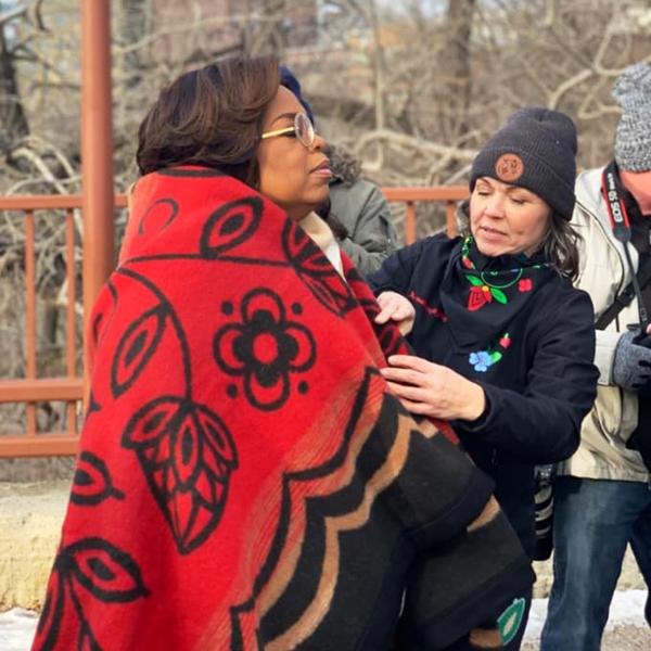 Here Sarah wraps Oprah in the Renewal wool blanket she designed. Taken by Wendi Baldwin.